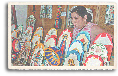 A Hispanic woman displays her colorful santos (retablos) at the annual Spanish Market on the historic Plaza in downtown Santa Fe, New Mexico. The depiction of Saints is theme commonly used in this traditional Spanish art form.