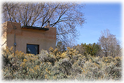 An adobe house on the outskirts of Taos, New Mexico, is surrounded by sagebrush and chamisa.